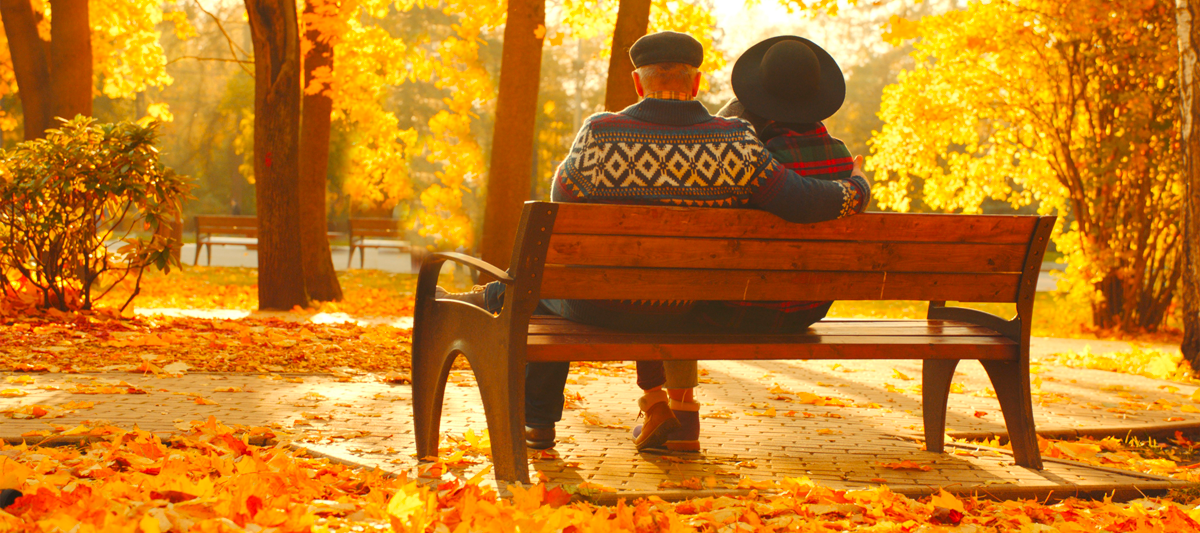 Postarší pár na lavičce v podzimním lese